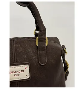 Detail of dark brown baguette bag featuring vintage gold hardware and a brand leather tag