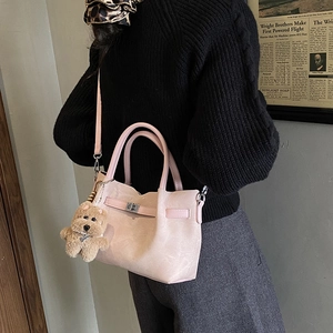 Detail of pink faux suede handbag with silver twist lock and brown teddy bear charm