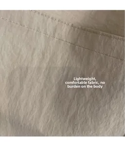 Detail view of lightweight beige fabric texture with precise double stitching craftsmanship