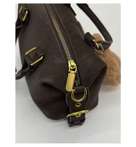 Detailed macro view of dark brown pebbled leather texture with retro gold hardware and pompom