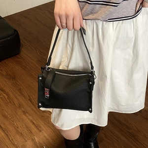 Detail of black lychee grain leather handbag with silver rivets and metal zipper