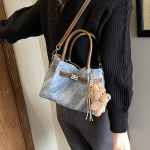 Close-up of vintage denim tote bag with leather straps and bear charm detail