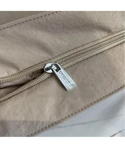 Close-up of smooth silver metal zipper and hardware on khaki nylon tote bag