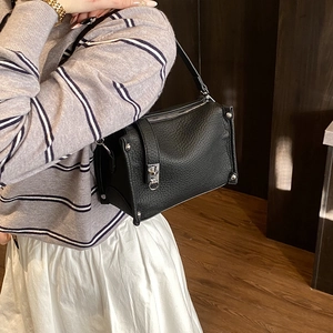 Close-up of black lychee texture leather boston bag with silver hardware and buckles