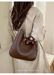 Minimalist dark brown leather tote bag with a dachshund charm and embossed logo detail