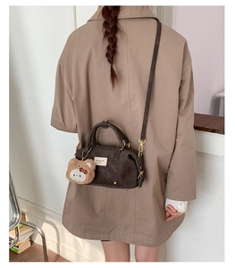 Detail of dark brown vintage Boston bag featuring a cute plush bear charm and gold hardware
