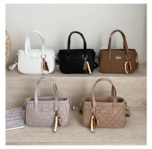 Détail de cinq sacs Boston colorés à texture tissée avec breloques de perles décoratives
