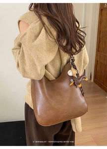 Close-up of vintage brown leather hobo bag with dachshund charm and silk ribbon detail