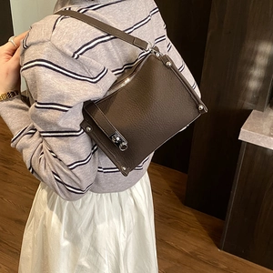 Detail of dark brown leather Boston bag showing silver twist lock and rivet accents