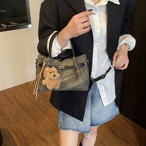 Detail of vintage canvas handbag featuring leather trim, metal twist lock and cute dog charm