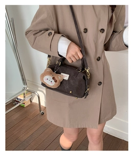 Detail of dark brown faux leather bowling bag with cute plush bear charm and woven label