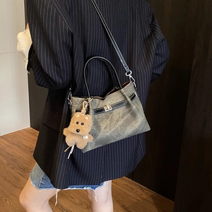 Detail of vintage gray-green tote bag with bronze buckle and cute brown bear charm