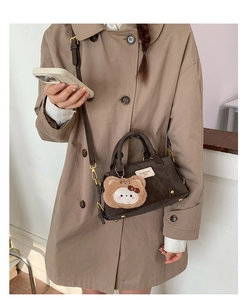 Detail of dark brown Boston bag with leather handles and a cute plush charm on a coat