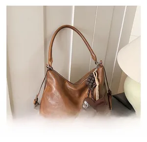 Gros plan d'un sac hobo en cuir PU marron avec bandoulière réglable et pendentifs