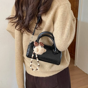Detail of black Boston handbag featuring cute plush bear charm and brown bead chain decoration