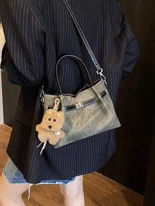 Vintage gray tote bag with black handles and puppy charm shown on a model in street style