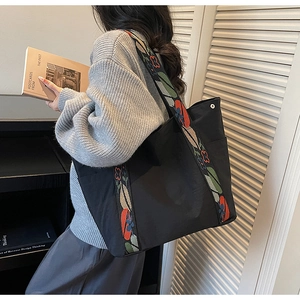 Detail of black tote bag with colorful ethnic floral embroidery on the wide shoulder strap
