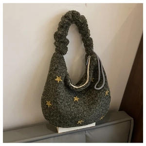 Dettaglio della borsa in peluche verde scuro con stelle gialle e manico arricciato
