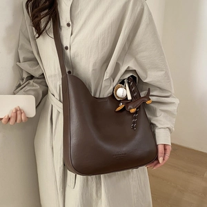 Large vintage dark brown leather crossbody hobo bag with baseball charm on model