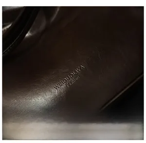 Gros plan sur le cuir marron brillant avec logo embossé sur le sac fourre-tout