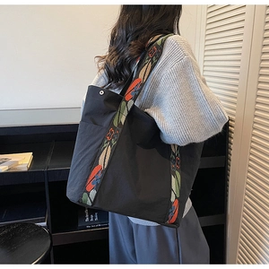 Detail of black canvas tote bag with decorative colorful embroidered wide shoulder strap