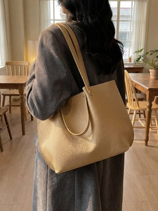 Minimalist khaki pleated tote bag with pebble leather texture in a cafe setting