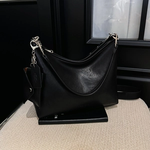 Détail du sac à bandoulière noir en cuir mat avec finitions et fermetures éclair argentées