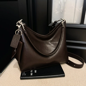 Détail du sac cabas en cuir marron foncé avec boucles argentées et logo embossé