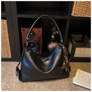 Dettaglio borsa hobo in pelle nera martellata con ciondolo a forma di cane marrone