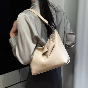 Détail du sac hobo en cuir crème avec boucles argentées et une petite breloque