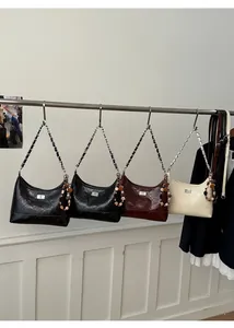 Multiple quilted chain bags in black, coffee, and white colors displayed on a rack