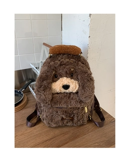 Detail of cute brown plush puppy backpack with curly fur and mini baguette charm