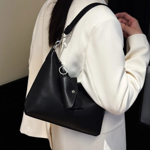 Détail du sac cabas en cuir noir minimaliste avec anneau argenté et mini pochette accessoire
