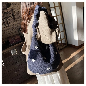 Borsa hobo blu in maglia con ricami a stella bianca in un ambiente interno stile vintage