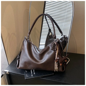 Dettaglio della grande borsa hobo marrone scuro con ciondolo a forma di cane e nappina