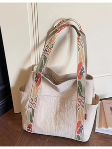 Off-white canvas tote bag featuring vintage floral embroidery on wide shoulder strap