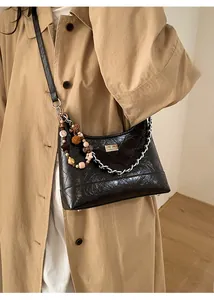 Close-up of brown quilted hobo bag with silver chain, metallic lock and decorative beads