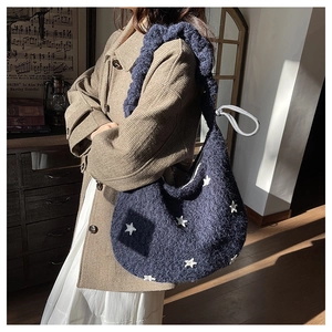 Dettaglio della borsa shopper in peluche blu navy con stelle bianche indossata da modella