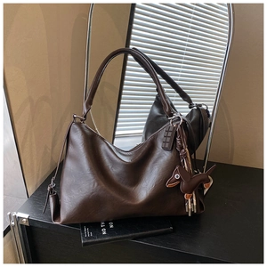 Dettaglio borsa tote marrone in PU con ciondoli a forma di cioccolato e bassotto