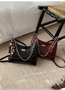 Quilted oil wax leather bucket bags in black and brown with metal chain details