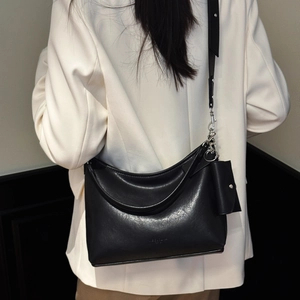 Détail du sac hobo noir avec boucles argentées et une petite pochette assortie sur l'épaule