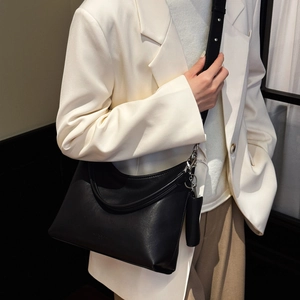 Sac fourre-tout noir mat porté par un mannequin en costume blanc pour une esthétique épurée