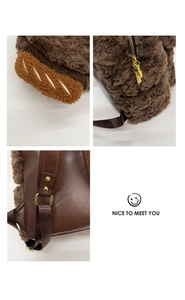 Detail of plush brown dog backpack with baguette charm and adjustable leather straps