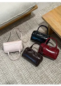 Detail view of four stylish Boston bags in pink, black, brown and red with chain straps