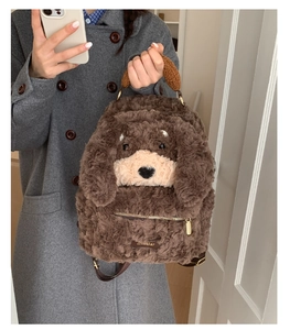 Detail of plush puppy backpack showing deep brown curly faux fur and metal zipper pocket