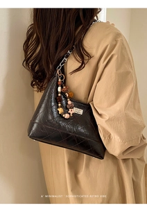 Detail of dark brown quilted leather underarm bag with silver chain and colorful beads