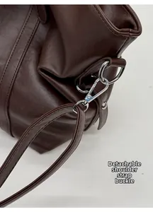 Detail of the silver metal swivel hook and detachable shoulder strap on brown leather tote
