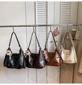 Four colors of minimalist leather tote bags with cute lion pendants hanging on a metal rack