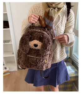 Detailed view of brown plush dog backpack with golden zipper and brand tag on model