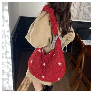 Borsa tote rossa in peluche con stella rosa e tracolla grigia indossata da una modella